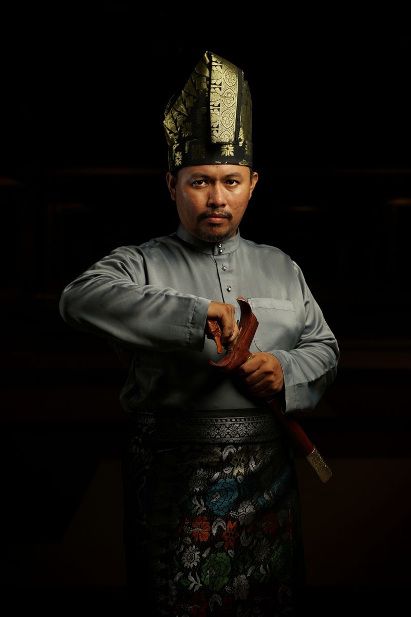 Man in traditional Malay attire holding a dagger