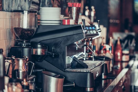 Modern coffee bar with espresso machine, stack of plates, and coffee accessories.