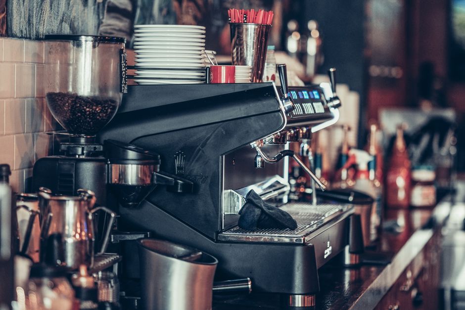 Modern coffee bar with espresso machine, stack of plates, and coffee accessories.