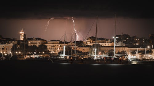 Lightning Strikes on a Dark Sky Over Buildings Near Boats