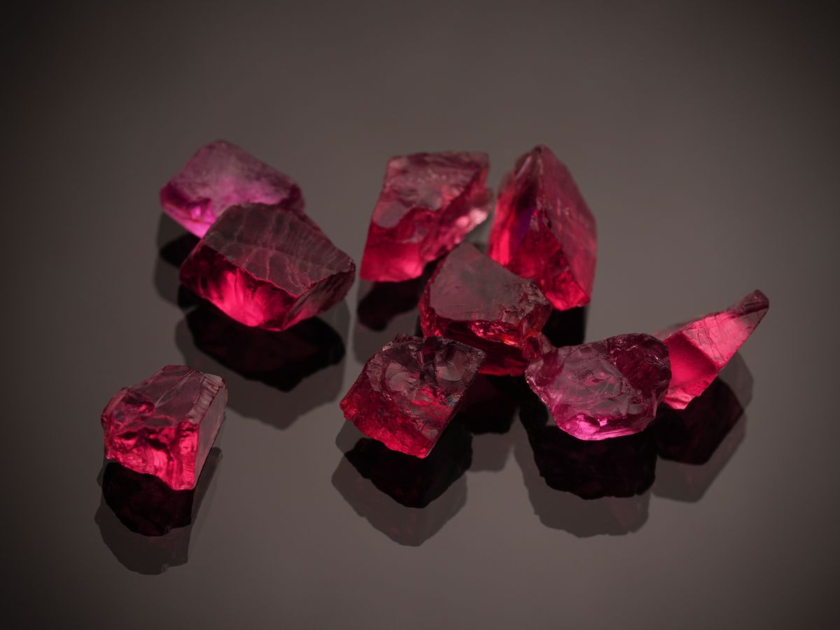 Faceted coloured gemstones arranged on a black surface
