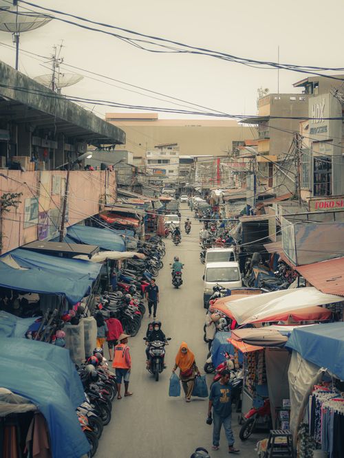 Free A lively street market scene in Sumatera Barat, Indonesia, with vendors, shoppers, and motorbikes. Stock Photo