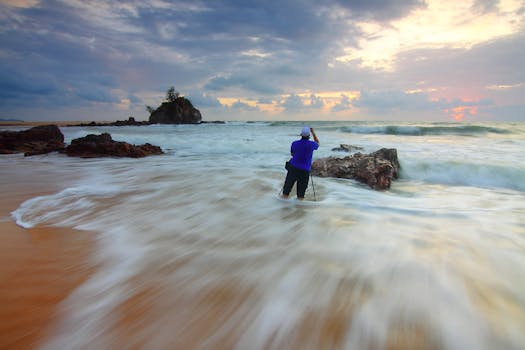 A person photographs the dynamic ocean waves at sunrise, creating a serene seascape view.