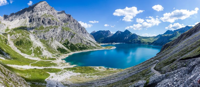 Breathtaking view of a serene alpine lake surrounded by rugged mountains under a clear blue sky.