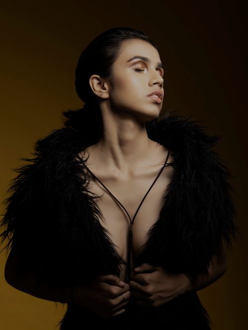 Free Sophisticated high fashion portrait of a model in a black feathered outfit, posing against a dark background. Stock Photo