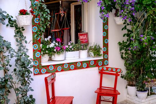 Free Colorful window sill decked with flowers and red chairs in Bozcaada, Turkey. Stock Photo
