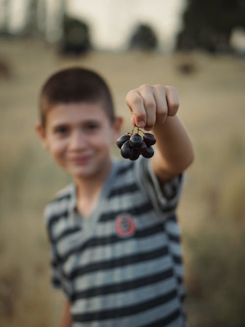 Boy Holding Grapes in Hand
