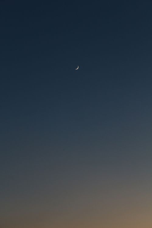 Free A peaceful crescent moon in the twilight sky, perfect for lunar or space themes. Stock Photo