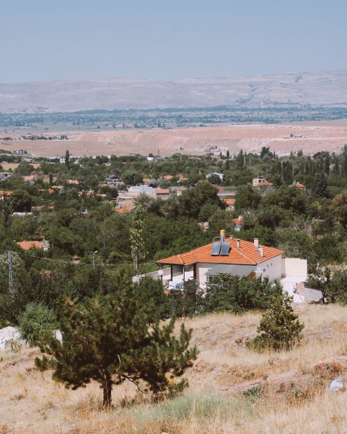 Free View of a serene rural town with scattered houses and lush greenery under a clear summer sky. Stock Photo