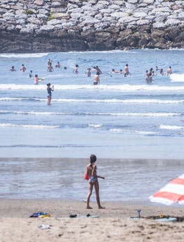 A lively summer day at Avilés beach with people enjoying the waves and sun.