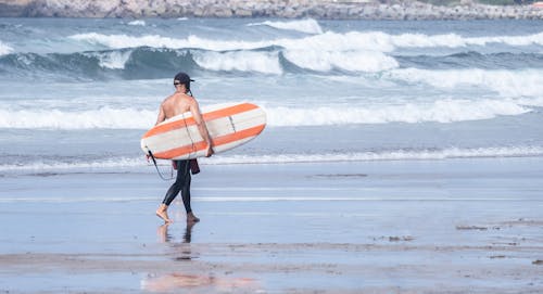 A Surfer Walking on the Beach