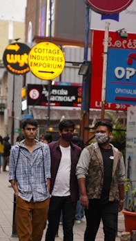 Three men walking in an urban street, wearing face masks amid city street signs.