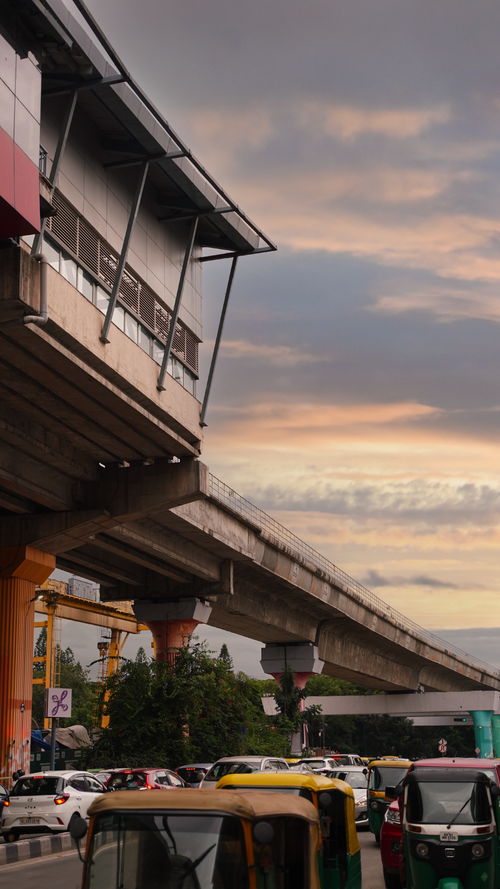 Free A modern elevated railway station above busy city traffic during a vivid sunset. Stock Photo