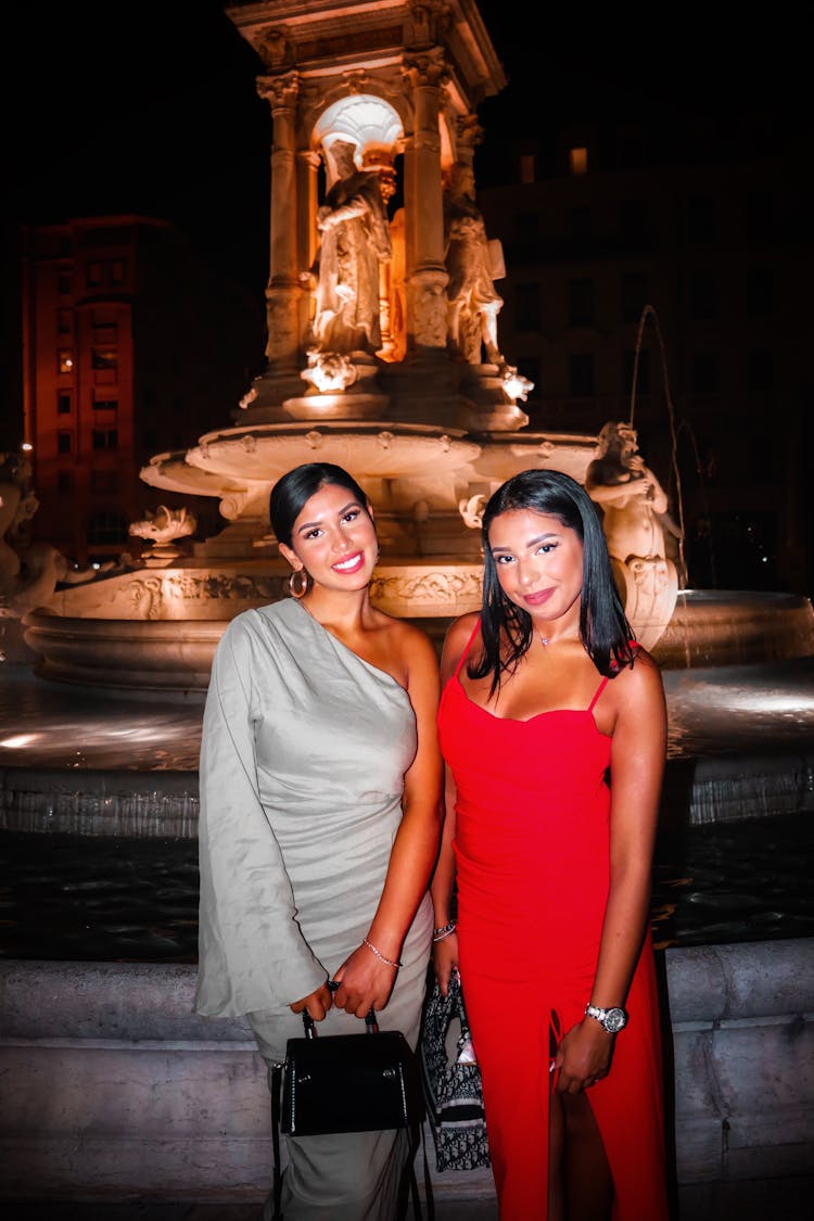 Elegant Women Standing In Front Of A Fountain