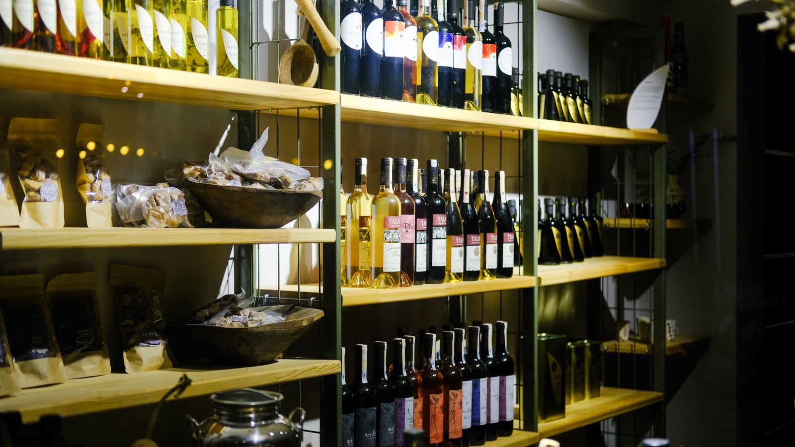 A variety of wine bottles displayed on wooden shelves in a Bozcaada retail store.