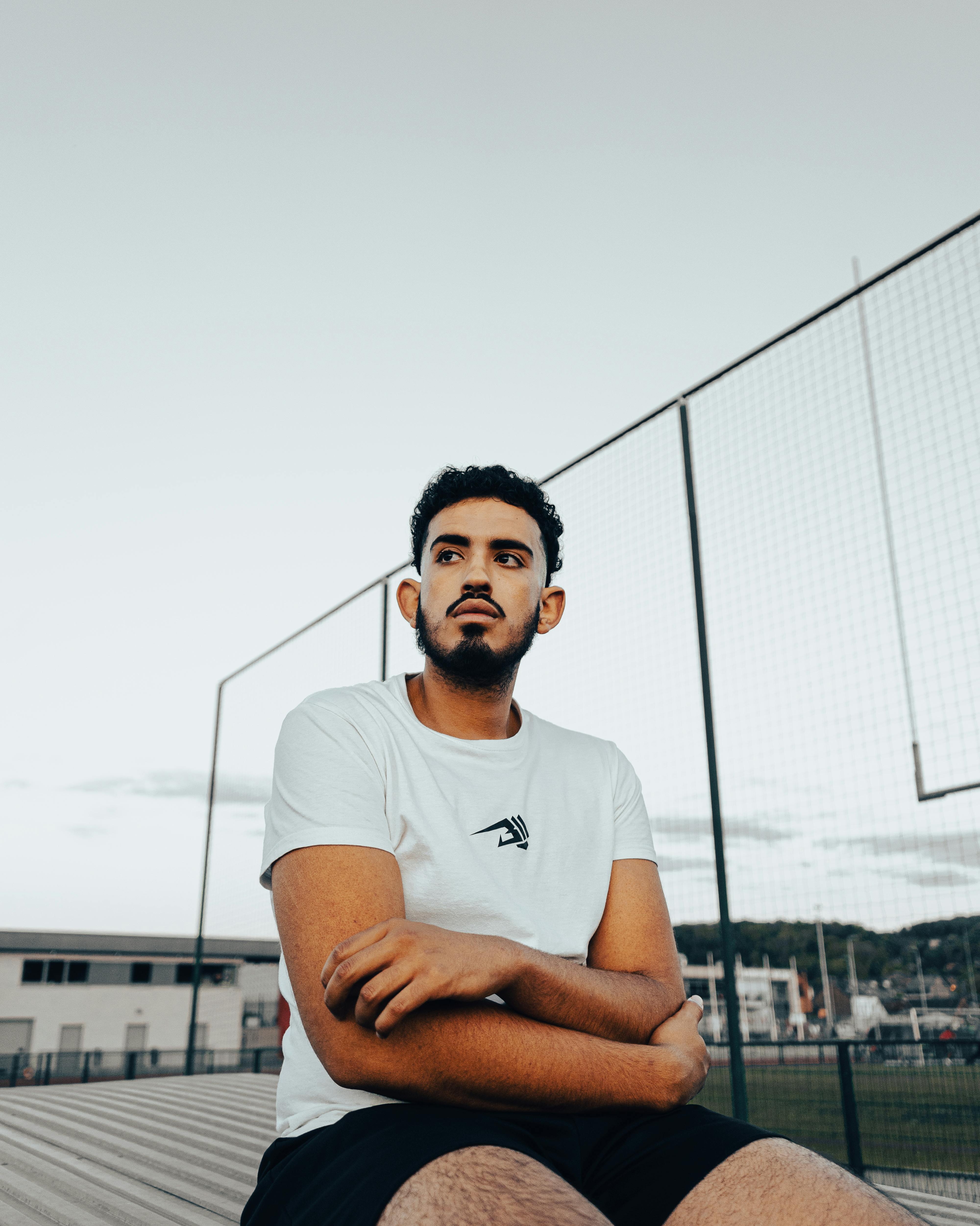 Portrait of a young bearded man in a white shirt sitting outdoors in Andenne, Belgium.