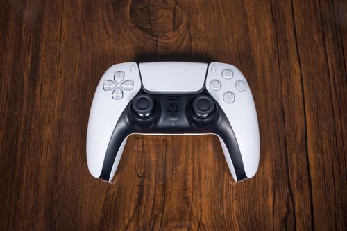 Free High-angle view of a sleek white game controller resting on a wooden surface, ideal for gaming themes. Stock Photo