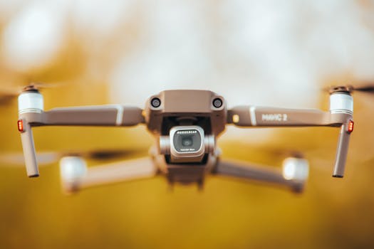 A detailed close-up of a drone in flight with a camera, set against a blurred outdoor backdrop.