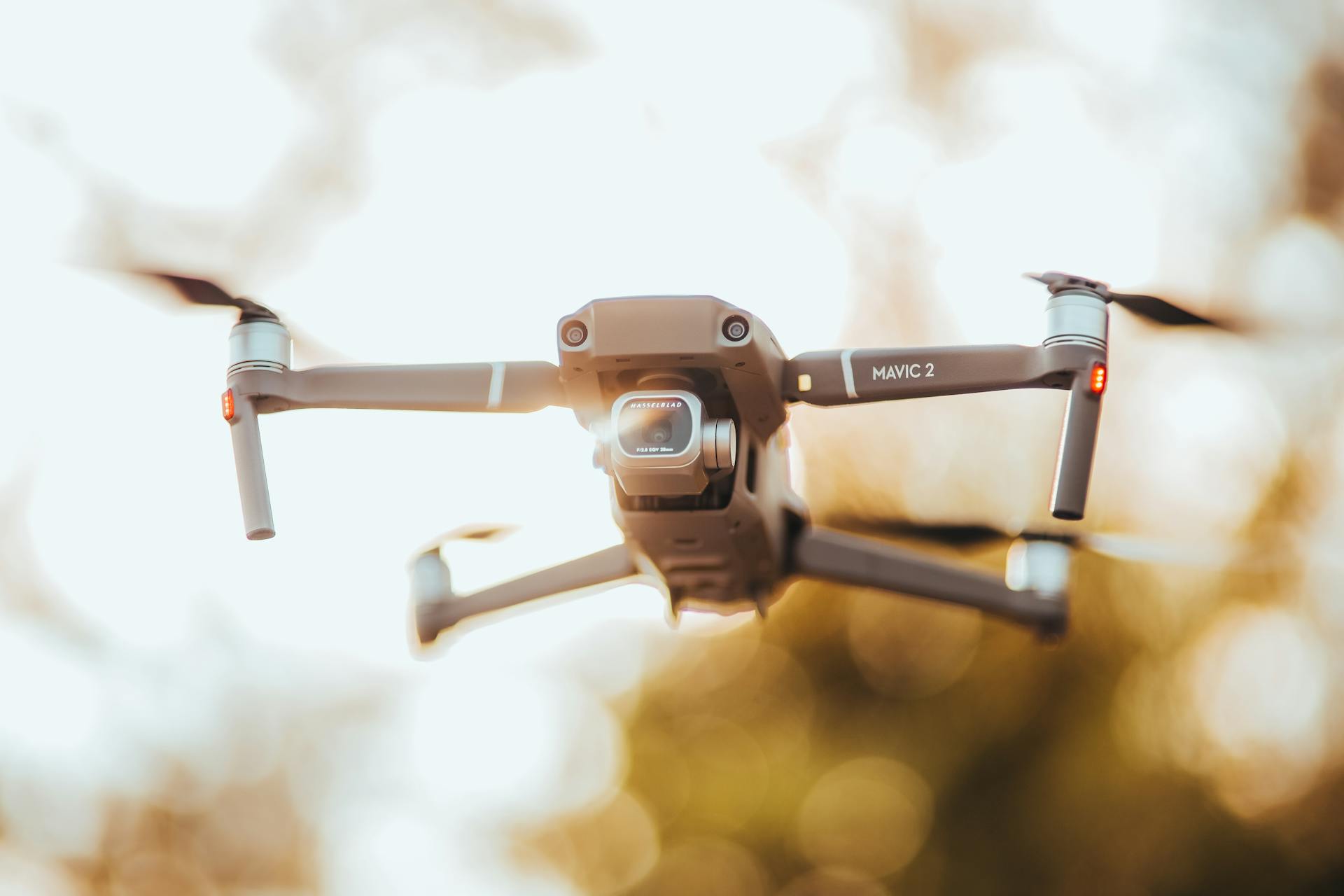 A detailed close-up of a DJI Mavic 2 drone flying outdoors in golden light.