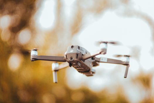 Close-up of a drone flying outdoors against a blurred autumn background.