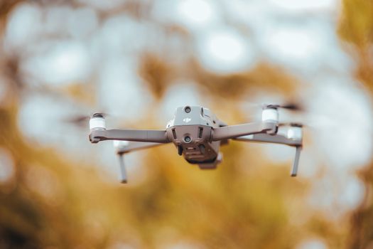 A detailed image of a drone in flight with a blurred natural background, captured outdoors.