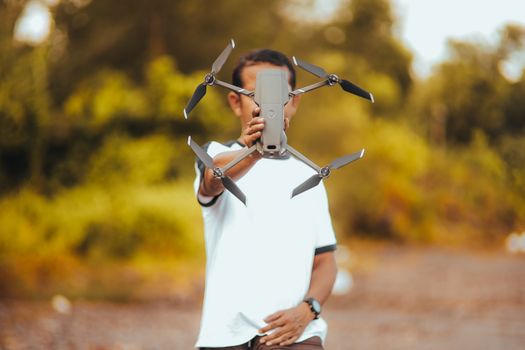 Man holding a drone in an outdoor environment, showcasing its features.