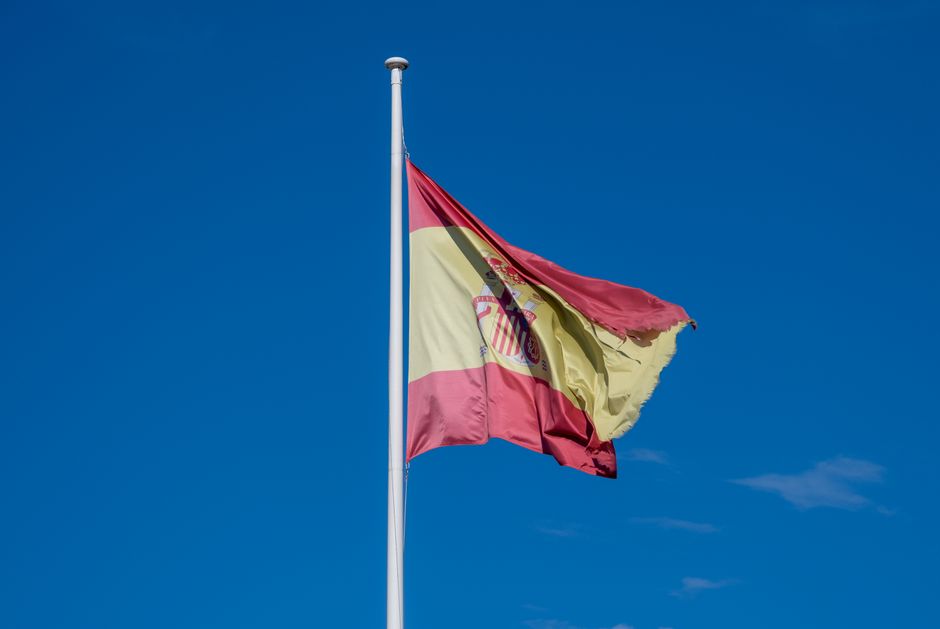 Bandeira española vibrante ondeando contra un cielo azul claro, capturada en un día soleado.