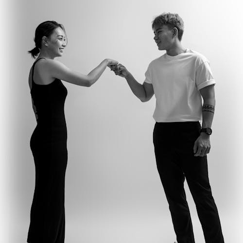 Grayscale Photo of Man and Woman Doing Fist Bump