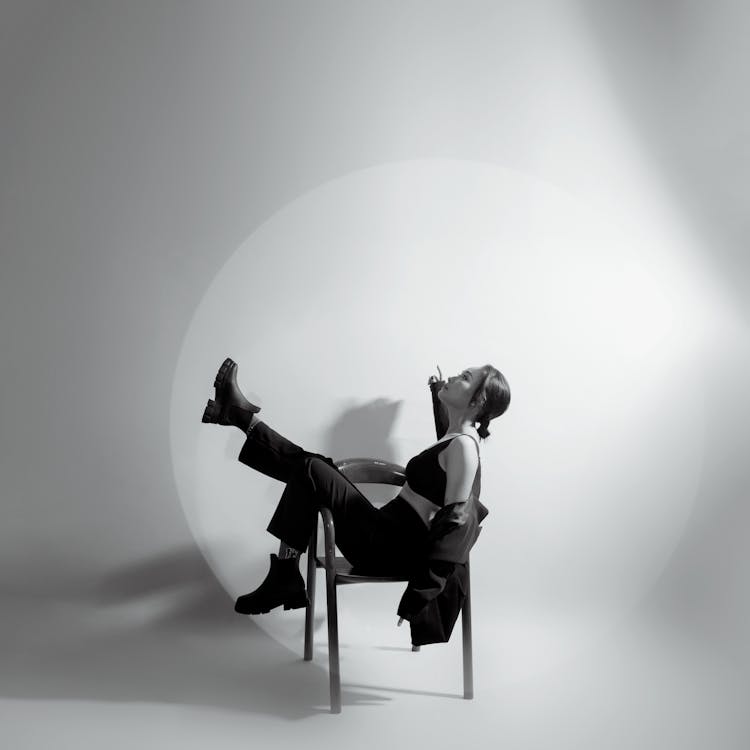 Young Woman Sitting On Chair Posing In Studio