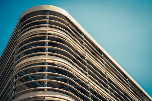 Free Low angle view of a contemporary building facade with sleek curves against a blue sky. Stock Photo