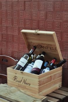A collection of wine bottles in a wooden crate labeled Pinot Nero Toscana, ideal for Tuscany wine enthusiasts.