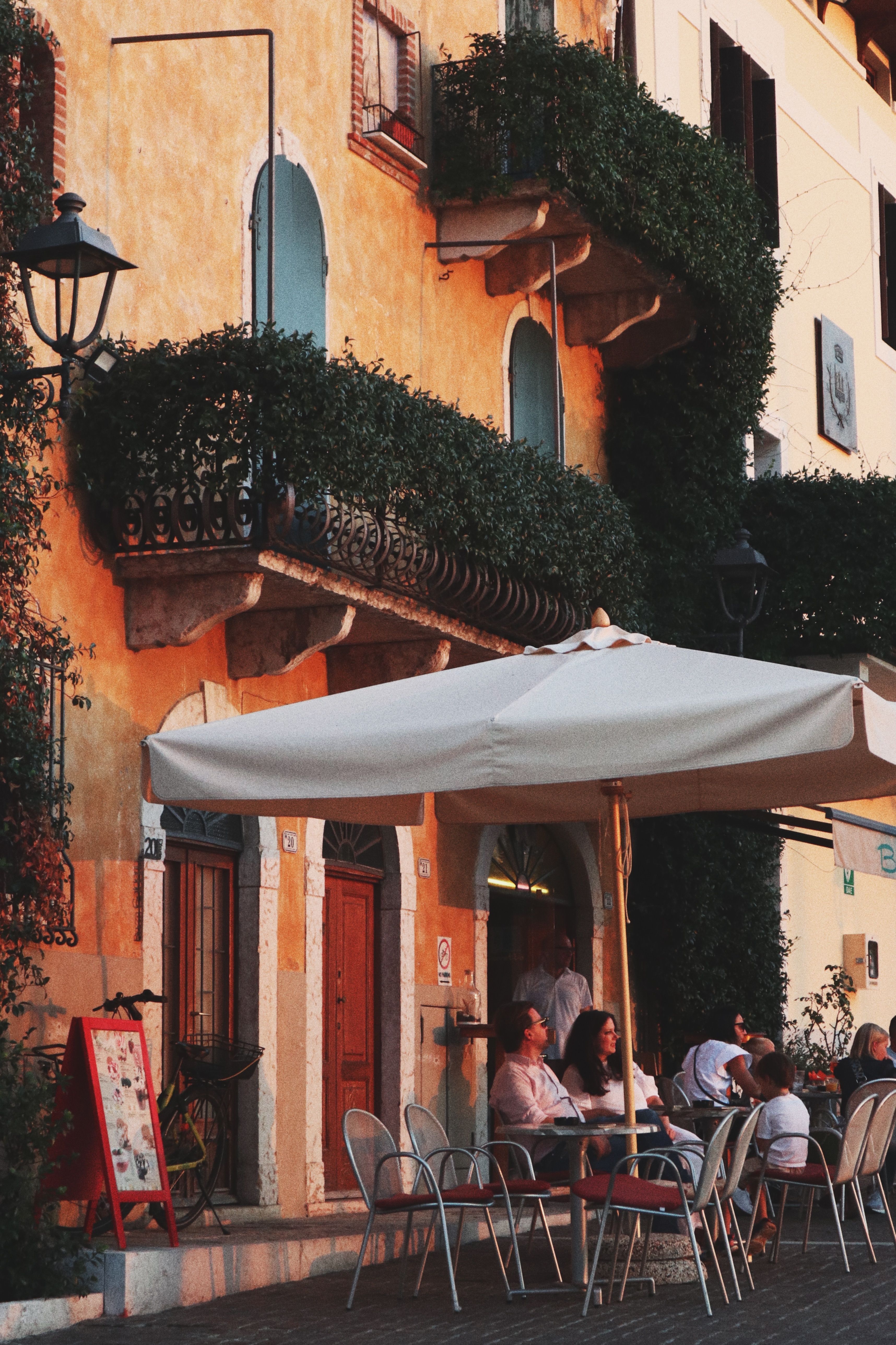 People dining outside a cafe beside warm-toned historic buildings
