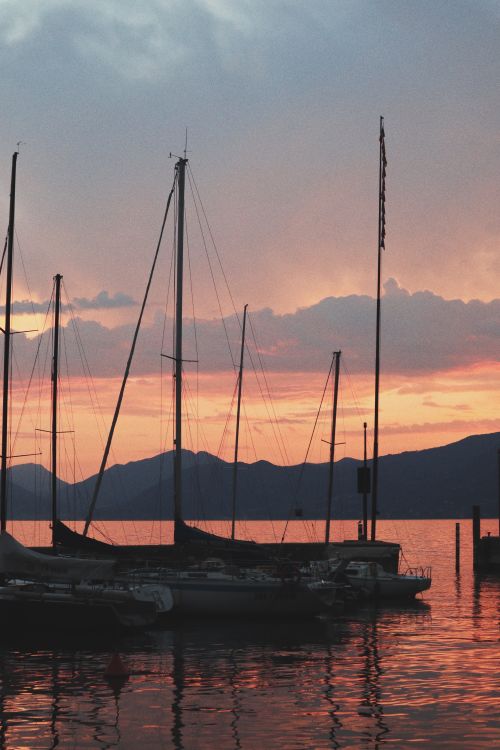 Free Silhouetted boats anchored on a calm sea with a colorful sunset backdrop. Tranquility and beauty. Stock Photo