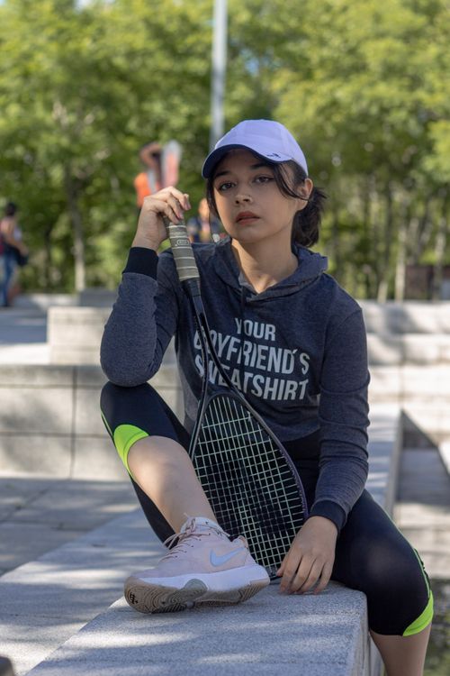 Free Young woman in athletic wear posing with a tennis racket outdoors. Stock Photo
