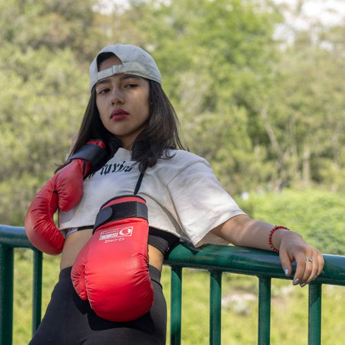 Free Outdoor portrait of a woman in sportswear and boxing gloves leaning on a railing. Stock Photo