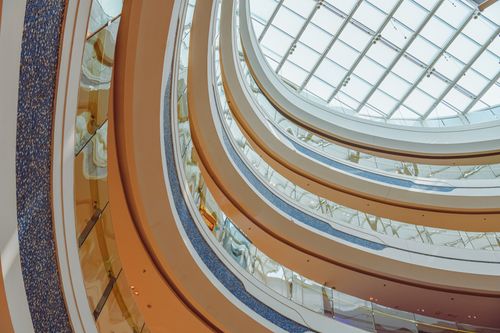 Free Elegant view of a shopping mall's balconies and glass skylight showcasing modern architecture. Stock Photo