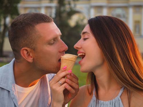 Free A couple sharing an ice cream cone on a sunny day, depicting love and connection. Stock Photo