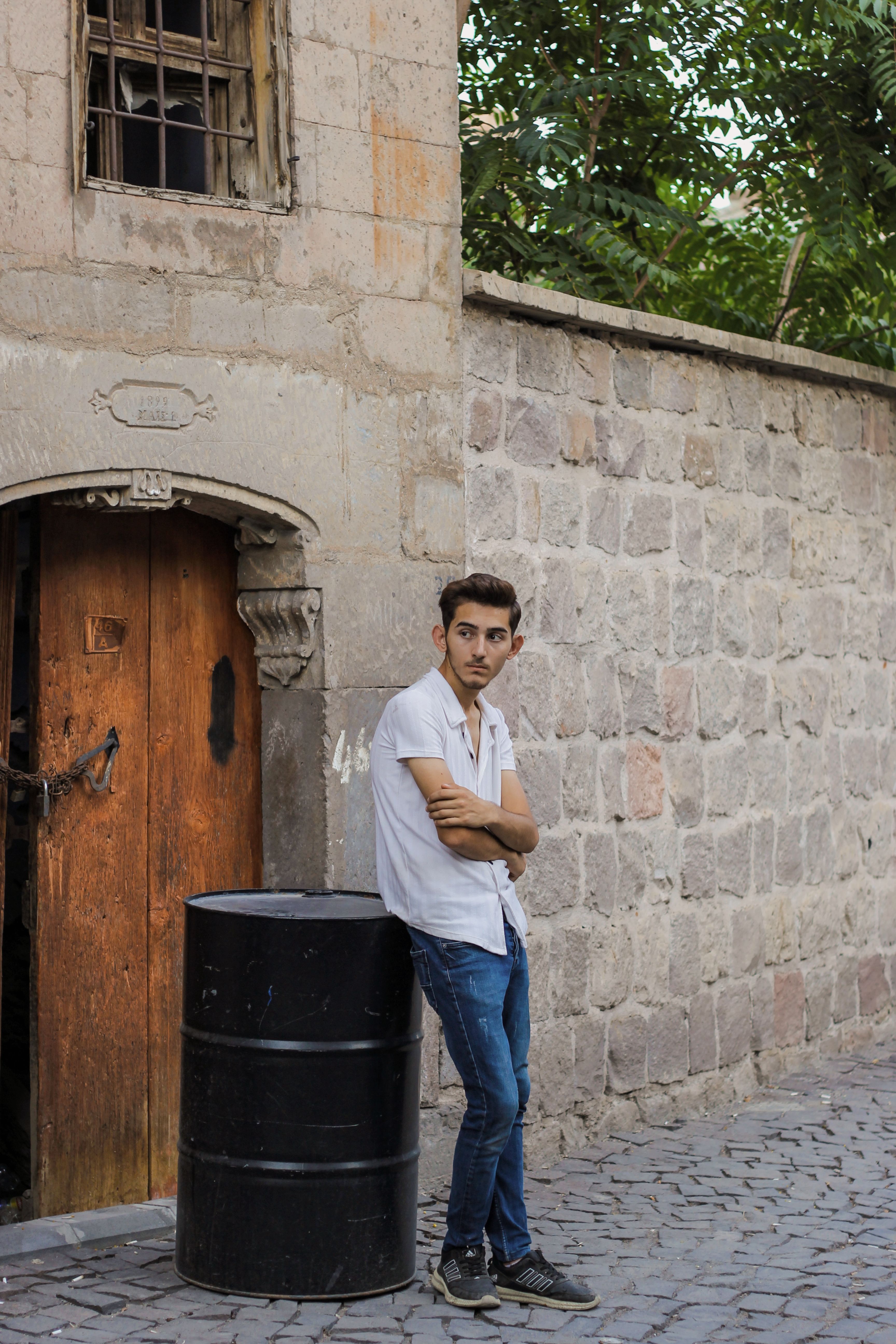 A young man leans casually against a stone wall in Talas, Turkey, exuding a relaxed and thoughtful demeanor.