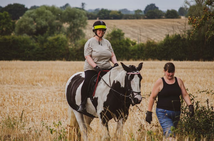 Woman In Helmet Riding Horse In Field