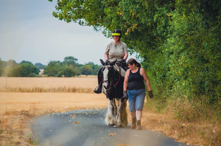 Woman Horseback Riding And The Other Woman Walking Next To The Horse 