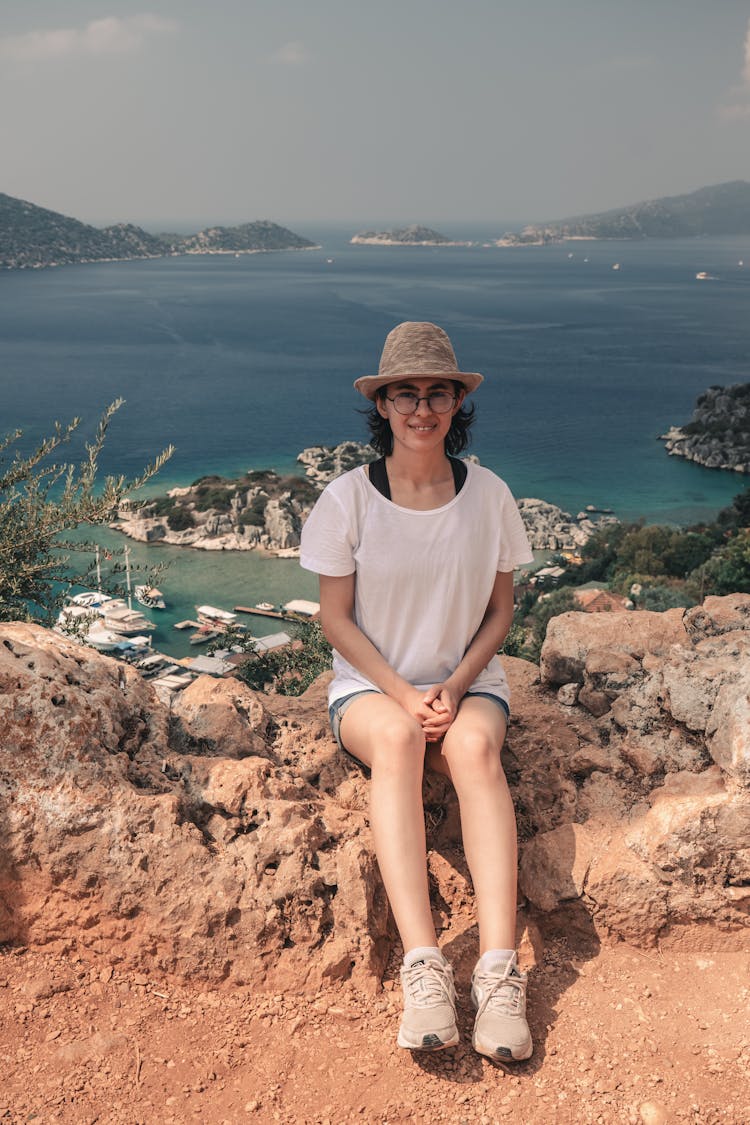 Smiling Woman Sitting On The Edge Of Sea Cliff