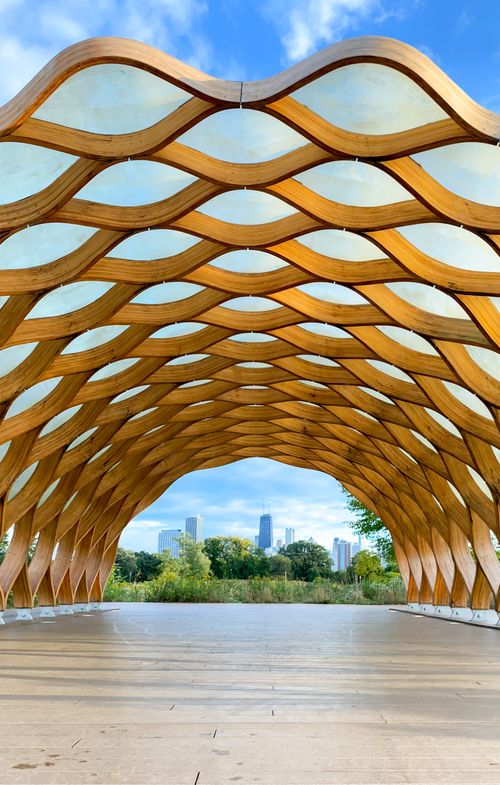 Free Modern architectural pavilion with a unique design, framing a city skyline view against a blue sky. Stock Photo
