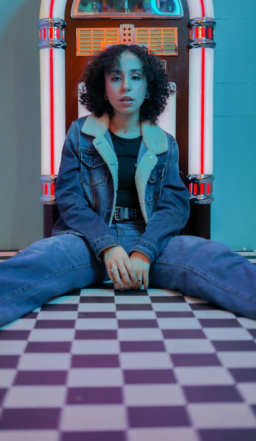 A Woman in Denim Clothes SItting on the Floor