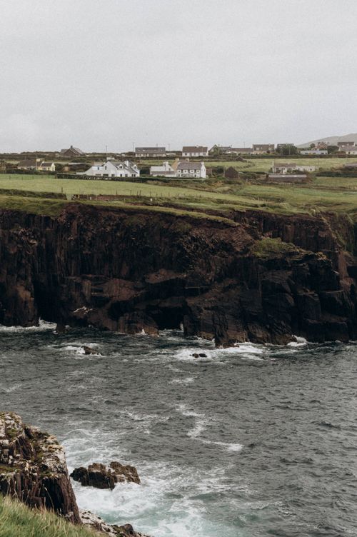 Free Charming coastal village with white houses atop rugged cliffs by the sea in a serene rural setting. Stock Photo