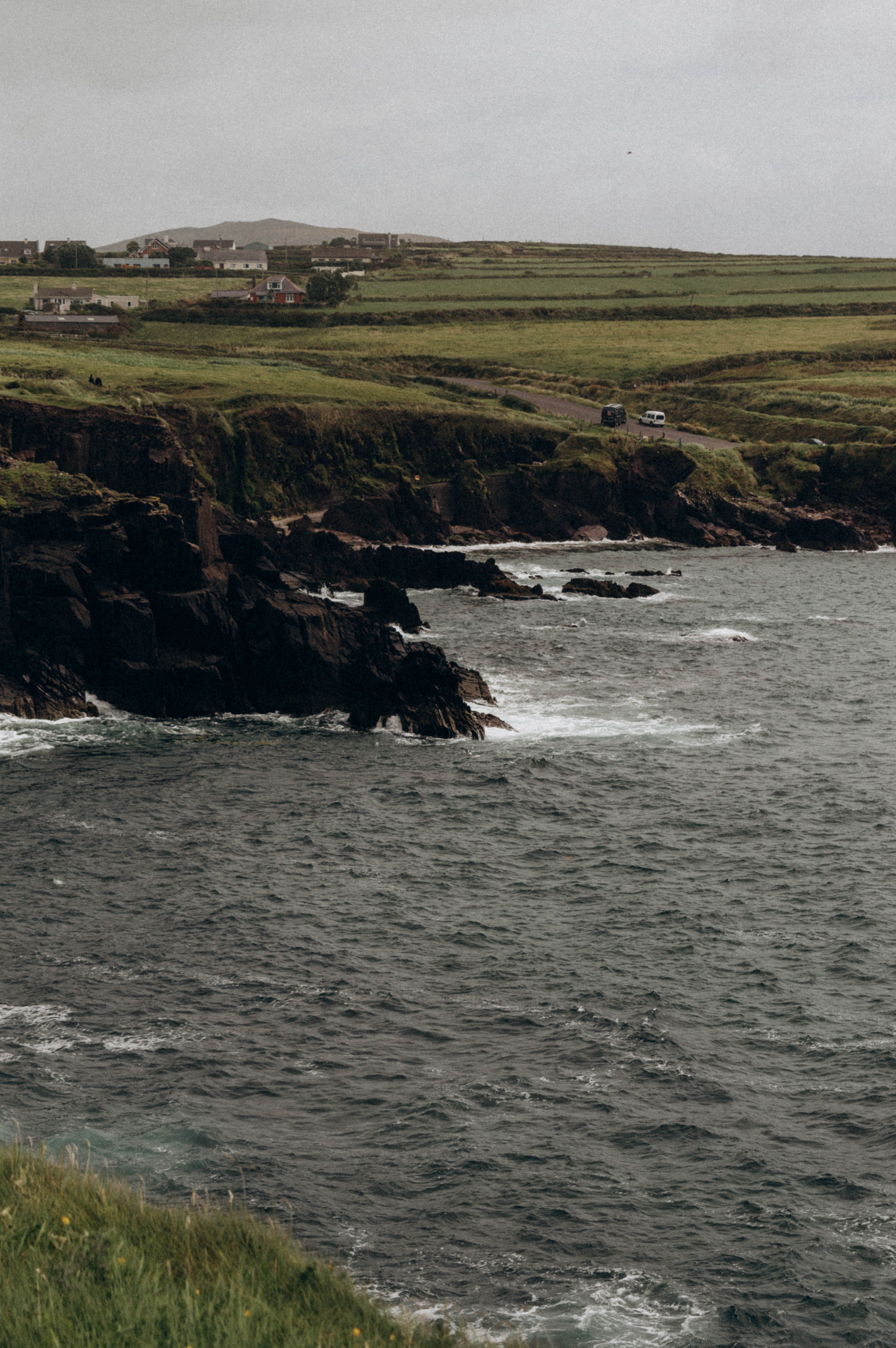 Dramatic cliffs and lush green headlands meet the ocean's waves.
