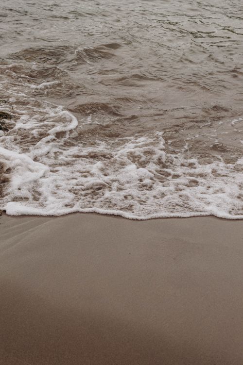 Free Close-up of gentle waves lapping a sandy beach, creating a tranquil coastal scene. Stock Photo
