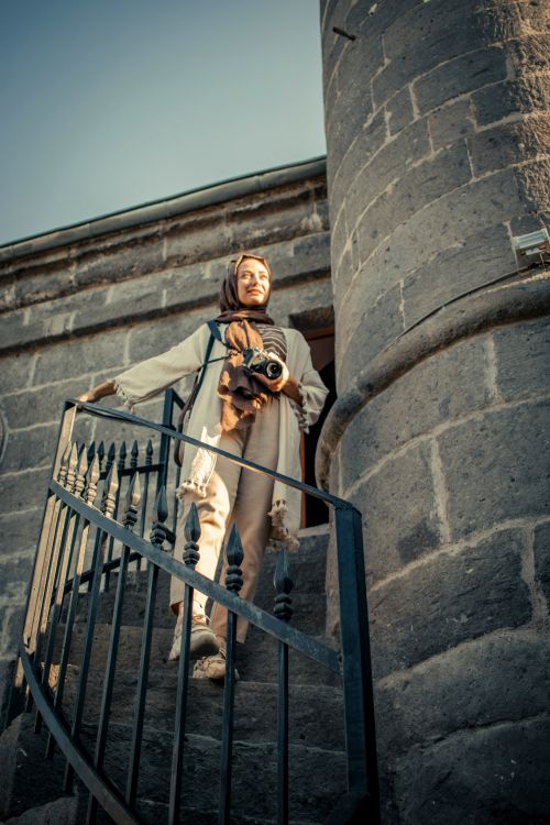 Free Woman in modest clothing holding camera on a spiral staircase in Kayseri, Türkiye. Stock Photo