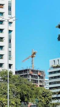 A vibrant cityscape of Recife featuring a tower crane amidst modern buildings on a clear day.