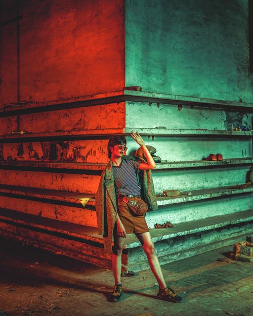 Free Model striking a stylish pose against a grungy urban wall, with colorful lighting effects. Stock Photo