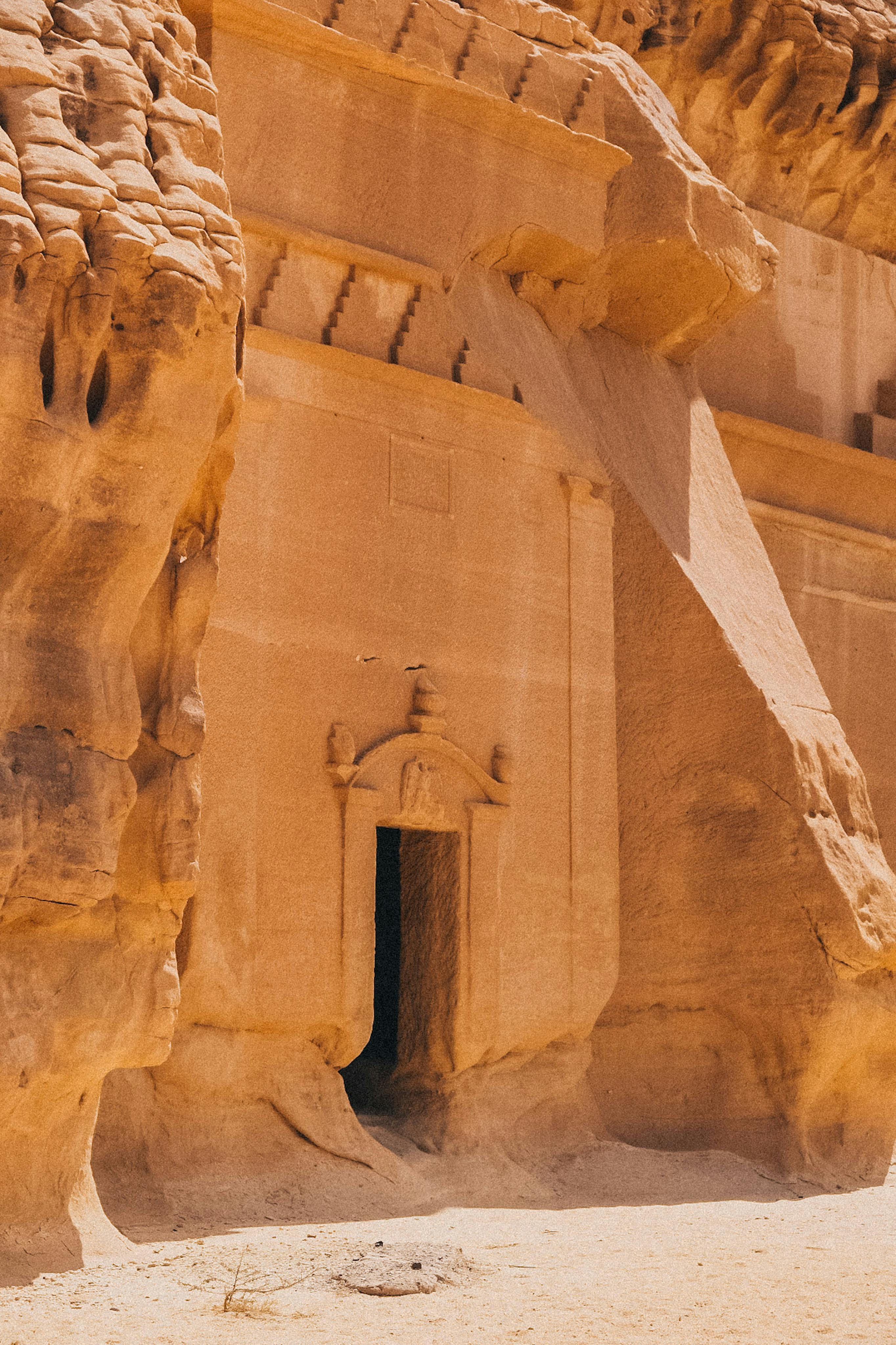 A historic stone tomb entrance carved into the desert rock, showcasing ancient architecture.